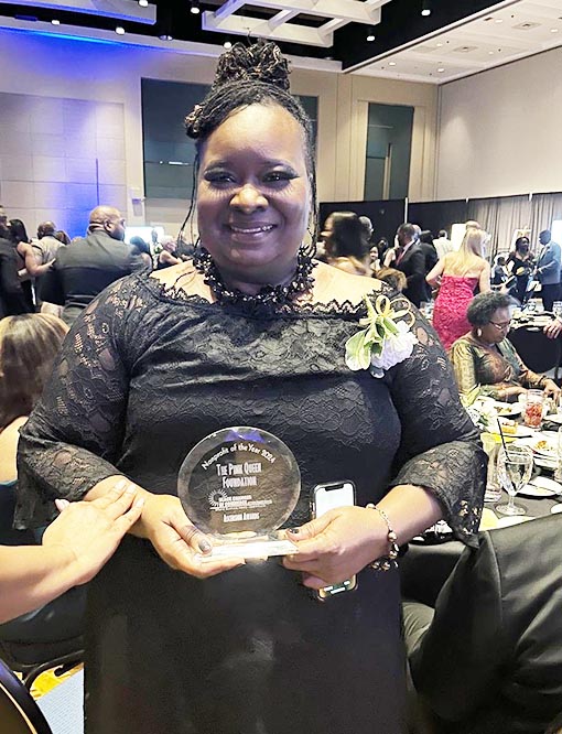 Smiling woman in black dress holding award